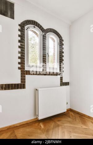 Cet appartement de style classique est doté de fenêtres voûtées, de murs blancs et de parquet en bois à la lumière du jour Banque D'Images