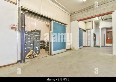 Intérieur de couloir spacieux d'entrepôt moderne avec portes coulissantes bleues et échelle dans le bâtiment industriel Banque D'Images