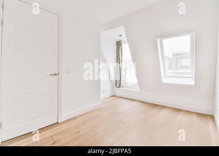 Intérieur d'un salon vide spacieux avec murs blanchis à la chaux, sol stratifié et portes blanches Banque D'Images