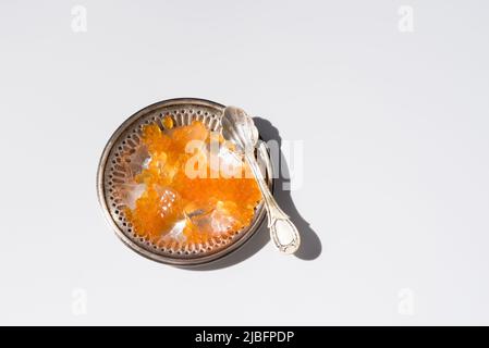 Du dessus de l'orange tobiko caviar servi sur une plaque argentée avec de la glace avec une cuillère sur fond blanc Banque D'Images