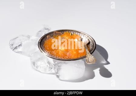 Du dessus de l'orange tobiko caviar servi sur une plaque argentée avec de la glace avec une cuillère sur fond blanc Banque D'Images