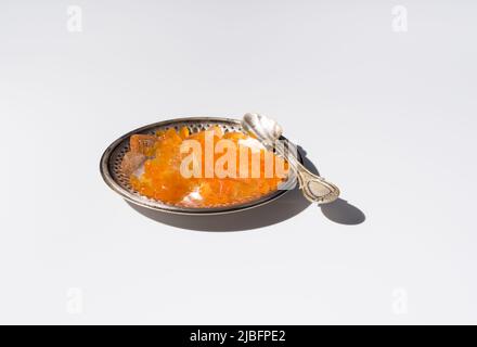 Du dessus de l'orange tobiko caviar servi sur une plaque argentée avec de la glace avec une cuillère sur fond blanc Banque D'Images