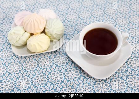 Un délicieux thé infusé traditionnel dans une tasse et des guimauves multicolores se trouvent sur une table, un dessert sucré Banque D'Images