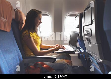 Femme utilisant un ordinateur portable pendant qu'elle est assise dans un avion près de la fenêtre Banque D'Images