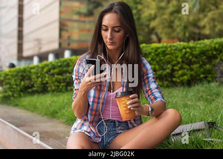 Jeune femme concentrée tapant un message texte sur son téléphone mobile à l'extérieur. Femme sérieuse utilisant un smartphone Banque D'Images