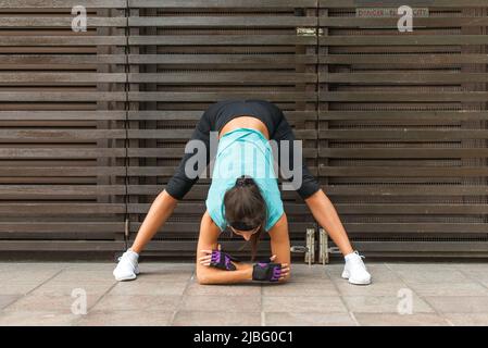 Sportive belle jeune femme pratiquant le yoga faire une posture de virage large vers l'avant, prasarita padottanasana stretching exercice, à l'extérieur sur la rue de la ville Banque D'Images