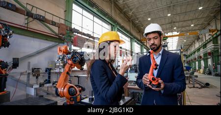 Homme ingénieur tenant le modèle de bras robotique industriel et montrant à collegue en usine. Banque D'Images