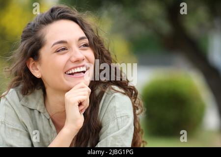 Bonne femme de beauté en train de rire assis dans un parc qui regarde à côté Banque D'Images