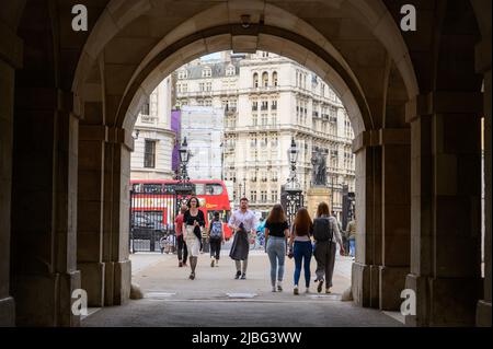 LONDRES - 18 mai 2022: Les gens marchent à travers l'arche d'entrée à la parade des gardes à cheval avec le bus à impériale rouge de Londres en arrière-plan Banque D'Images