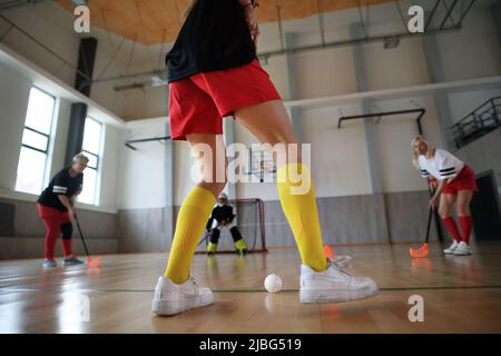 Basse section de la femme, joueur de floorball pendant le match dans la salle de gym. Banque D'Images