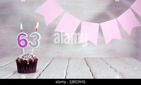 Numéro d'anniversaire. Fond festif pour une fille ou une femme avec un muffin et des bougies brûlant rose dans des couleurs pastel avec des décorations pour n'importe quel jour de vacances, Banque D'Images