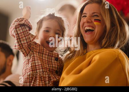 Fans de football enthousiastes, mère avec petite fille, en défendant l'équipe nationale allemande lors d'un match de football en direct au stade. Banque D'Images