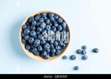 Bleuets biologiques dans un bol sur fond bleu dégradé, vue du dessus de l'espace de copie Banque D'Images