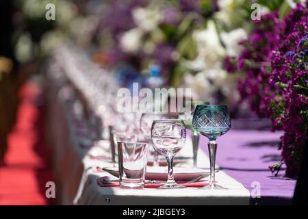 Décoration table de fête avec fleurs violettes et blanches et verrerie sur nappe. Mise au point sélective Banque D'Images