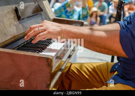 Les mains et les clés du pianiste jouent le piano avec une foule floue en arrière-plan au French Quarter Festival à la Nouvelle-Orléans, LA, États-Unis Banque D'Images
