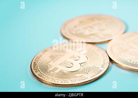 Gros plan de trois bitcoins d'or sur fond plat. Banque D'Images