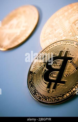 Gros plan de trois bitcoins d'or sur fond plat. Banque D'Images