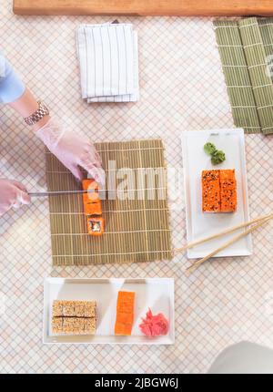 Vue de dessus du chef professionnel qui prépare et sert des petits pains à sushis californiens dans la cuisine. Banque D'Images