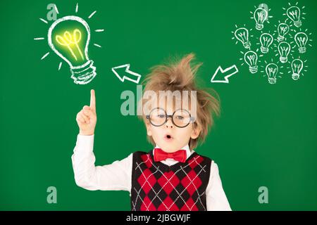 Drôle d'enfant étudiant en classe. Un enfant heureux contre un tableau noir vert. Concept d'éducation. Retour à l'école Banque D'Images