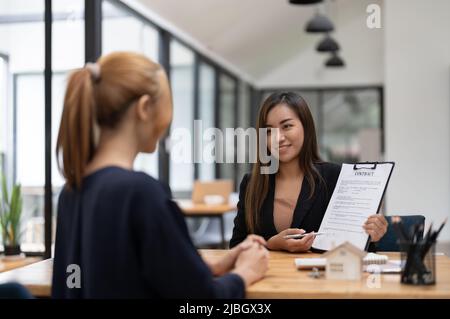 Les acheteurs de maison rencontrent et négocient avec les agents immobiliers au sujet de la location ou de l'achat d'une maison dans le bureau. Concept d'accord de contrat. Banque D'Images