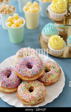 Vue en grand angle des beignets avec glaçage au sucre sur l'assiette avec des petits gâteaux en arrière-plan servis sur la table de vacances Banque D'Images