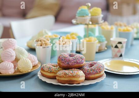 Gros plan de beignets glacés, guimauves, petits gâteaux sur les assiettes servis sur la table de vacances pour la fête Banque D'Images