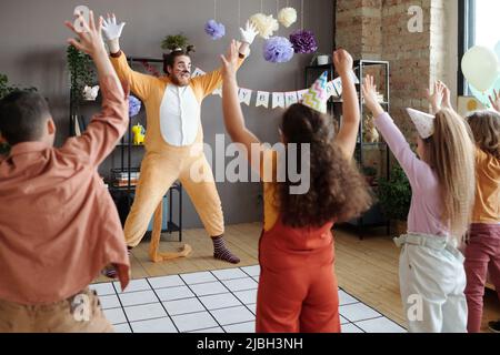 Amusant animateur en costume de chat danse et groupe d'enfants répéter des mouvements pour lui pendant la fête d'anniversaire Banque D'Images