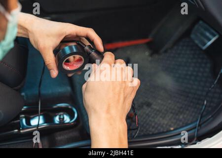 Main du mécanicien utilisant le ruban adhésif du fil d'emballage de la voiture pour installer le dispositif électronique Banque D'Images