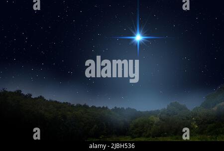 Le brouillard s'élève au-dessus de la forêt nocturne. L'étoile lumineuse indique la Nativité de Jésus-Christ dans le ciel étoilé. Banque D'Images