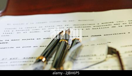 Stylo et stylo à bille sur une feuille de papier écrite sur une table de bureau Banque D'Images