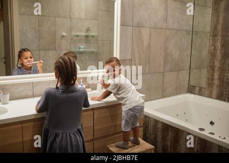 Portrait de deux enfants afro-américains dans la salle de bains se concentre sur le brossage des dents de petit garçon, l'espace de copie Banque D'Images