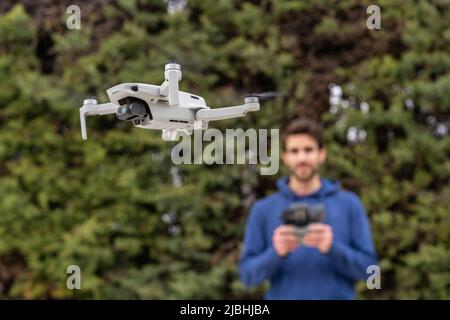 Jeune homme contrôlant un drone volant à l'extérieur du parc Banque D'Images