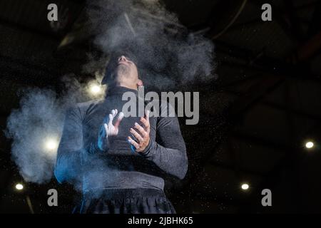 Jeune sportif mettant de la craie sur ses mains avant l'entraînement Banque D'Images