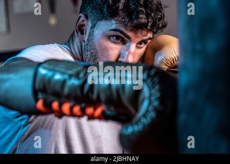 Le jeune boxeur caucasien s'est concentré sur le sac avec des gants de boxe avec des lacets Banque D'Images