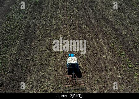 Vue aérienne du tracteur agricole labourage dans le champ, tracteur préparant le cultivateur de semis au printemps Banque D'Images