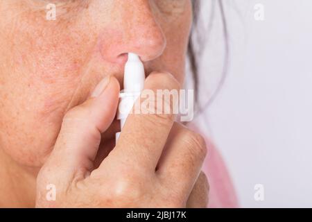 Gros plan des mains de la femme en utilisant un spray nasal. Banque D'Images