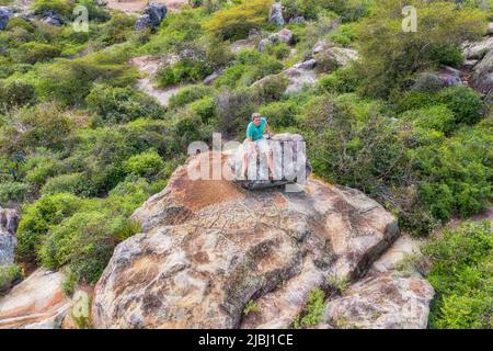 Vue aérienne d'un homme assis au sommet d'un plateau rocheux à Tobati, Paraguay. Banque D'Images