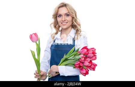 jeune femme positive en tablier avec fleurs de tulipe de printemps isolées sur fond blanc Banque D'Images