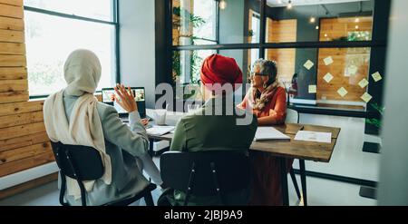 Femmes d'affaires multiculturelles assistant à une réunion en ligne dans un bureau moderne. Groupe de femmes d'affaires ethniques ayant une vidéoconférence avec leur bussin Banque D'Images