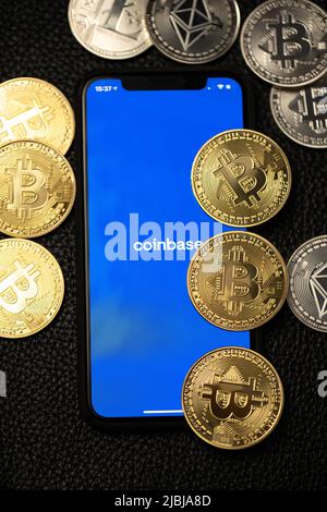 Bolzano, Italie - 10 avril. 2021: Application Coinbase sur smartphone à côté de bitcoin et de pièces de monnaie éthérée sur fond de cuir Banque D'Images