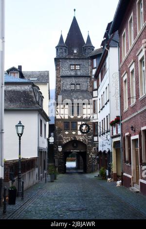 Rue pavée avec bâtiments historiques menant à une tour à Bacharach, Allemagne. Banque D'Images