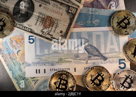 Toronto, Canada - 30 octobre. 2021: Billets en dollars AMÉRICAINS en plus de cinq dollars canadiens, pièces en bitcoin en bas. Négociation de crypto-monnaie avec les États-Unis Banque D'Images