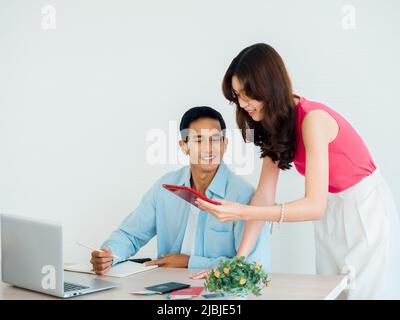 Joyeux couple asiatique, jeune homme et femme utilisant une tablette et un ordinateur portable ensemble pour la réservation de vol, la chambre d'hôtel et les informations de voyage à la maison, prêt t Banque D'Images