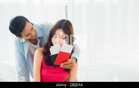 Couple de voyageurs en vacances heureux. Concept lune de miel de vacances d'été. Un couple asiatique souriant tenant et montrant un passeport, prêt à voyager, jeune femme an Banque D'Images