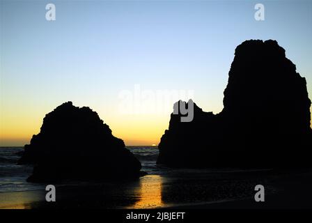 Les formations rocheuses de Rodeo Beach, près de San Francisco, sont rendues en silhouette contre un ciel de coucher de soleil Banque D'Images