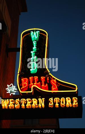 Un grand panneau avec des lumières au néon, en forme de cow-boy bottes attire les clients dans un magasin de l'Ouest à Dallas Texas Banque D'Images