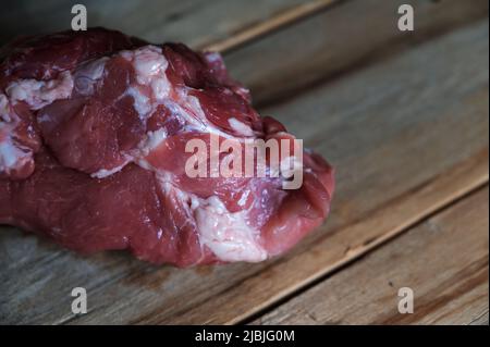 Porc cru sur fond de bois. Un morceau de porc tout-musclé repose sur le dessus de vieux planches fissurées. Mise au point sélective Banque D'Images