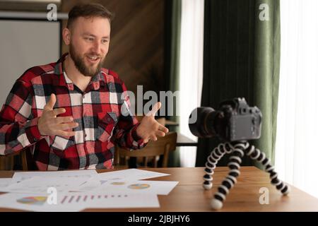 Homme dans la chemise montre stats graphique pad faisant la promotion videoblog ou session de photo dans le caméscope à trépied. Vlogger selfie solution de vente ou conseiller financier Banque D'Images