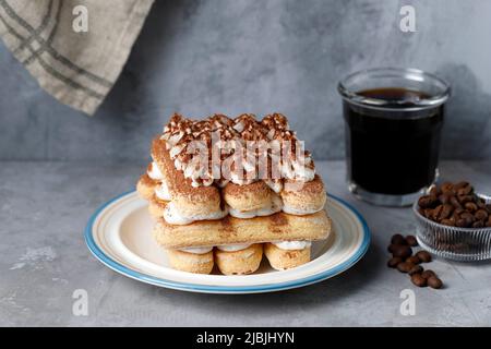 Gâteau Tiramisu maison avec Un verre de café noir, dessert italien sucré. Arrière-plan alimentaire avec espace de copie pour le texte Banque D'Images