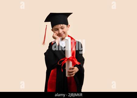 Whizz enfant 9-11 ans portant la casquette de remise des diplômes et la robe de cérémonie regardant le certificat papier de l'éducation. Еlementary garçon diplômé de l'école avec certificat Banque D'Images